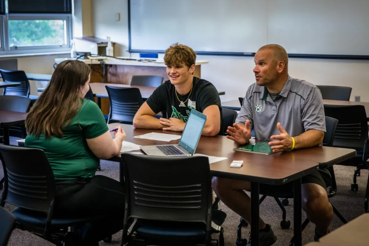 A student and a parent meet with their advisor to discuss class schedules.